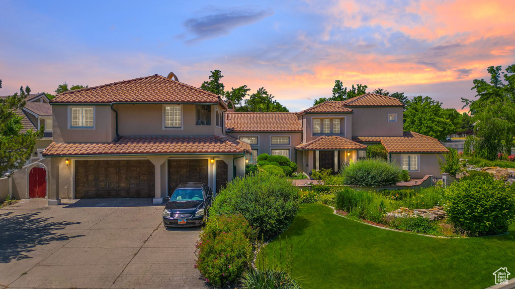 Mediterranean / spanish-style home featuring an attached garage, driveway, a tile roof, and stucco siding