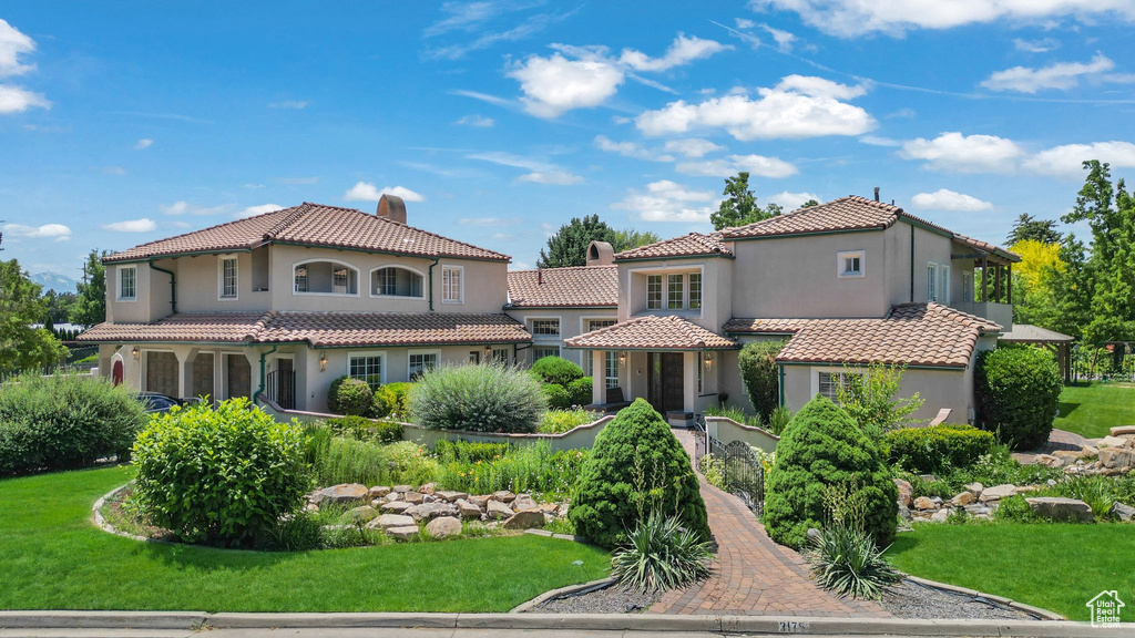 Mediterranean / spanish home with stucco siding, a tiled roof, and a front yard