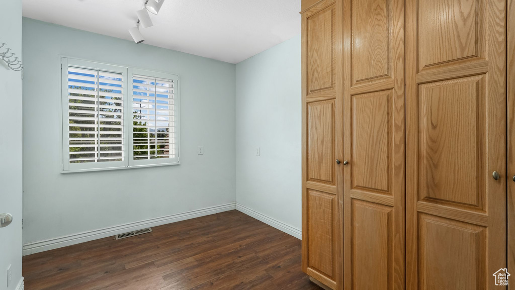 Unfurnished bedroom featuring dark wood finished floors and baseboards
