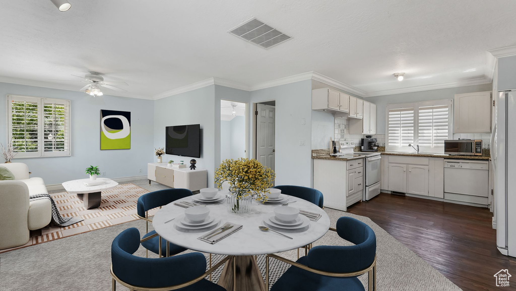 Dining area featuring ceiling fan, ornamental molding, and dark wood-style flooring
