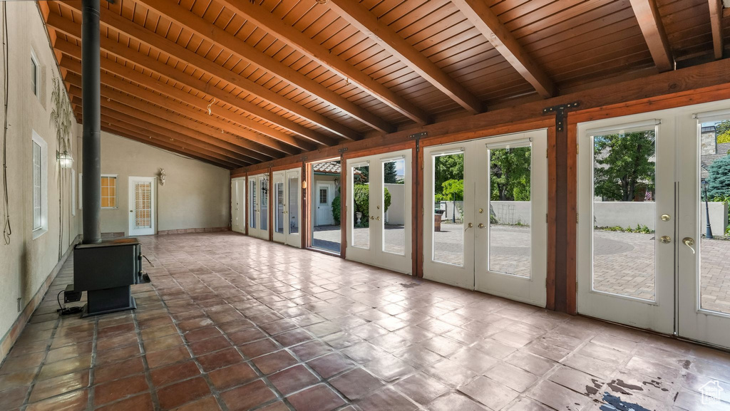 Unfurnished sunroom featuring french doors, a wood stove, and plenty of natural light