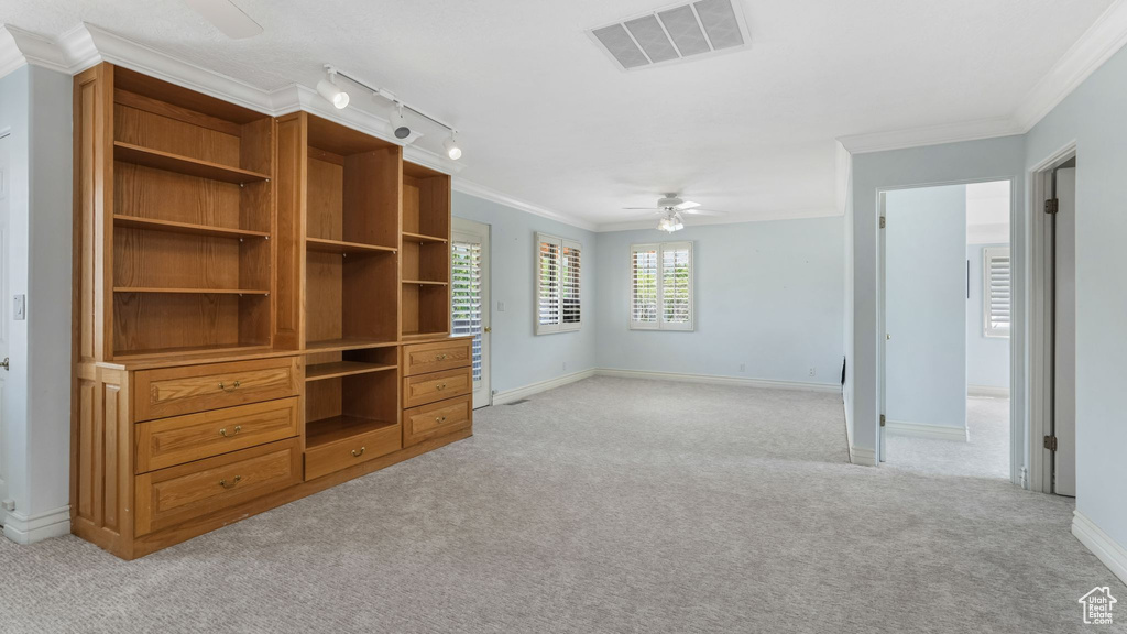 Unfurnished living room featuring ceiling fan, light carpet, ornamental molding, and rail lighting