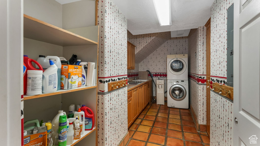 Laundry room featuring wallpapered walls and estacked washer and dryer