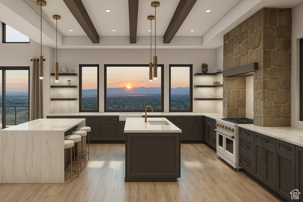 Kitchen featuring open shelves, double oven range, a center island with sink, beamed ceiling, and light stone counters