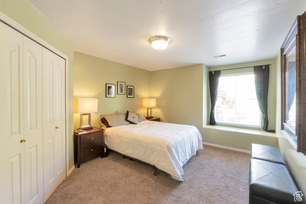 Bedroom with light colored carpet and a closet
