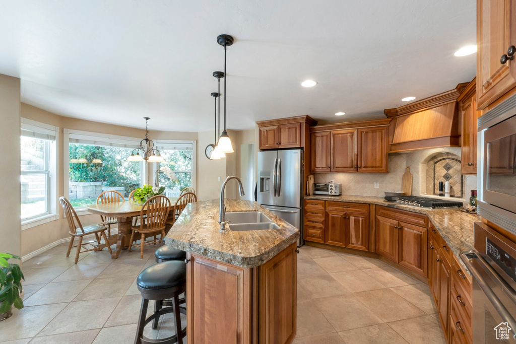 Kitchen with stainless steel appliances, brown cabinetry, plenty of natural light, light tile patterned flooring, and recessed lighting