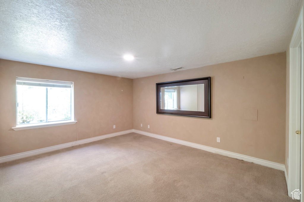 Empty room with carpet flooring and a textured ceiling