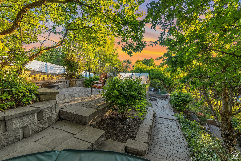 Pool at dusk featuring an exterior structure and a patio area