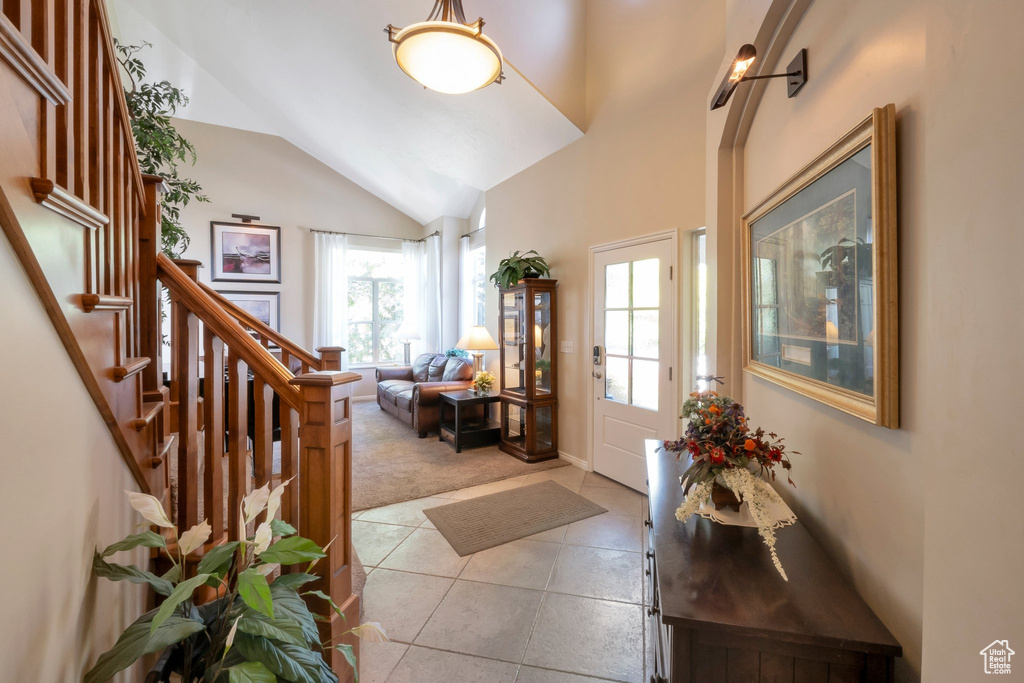 Foyer entrance with lofted ceiling, light tile patterned floors, light carpet, and stairs