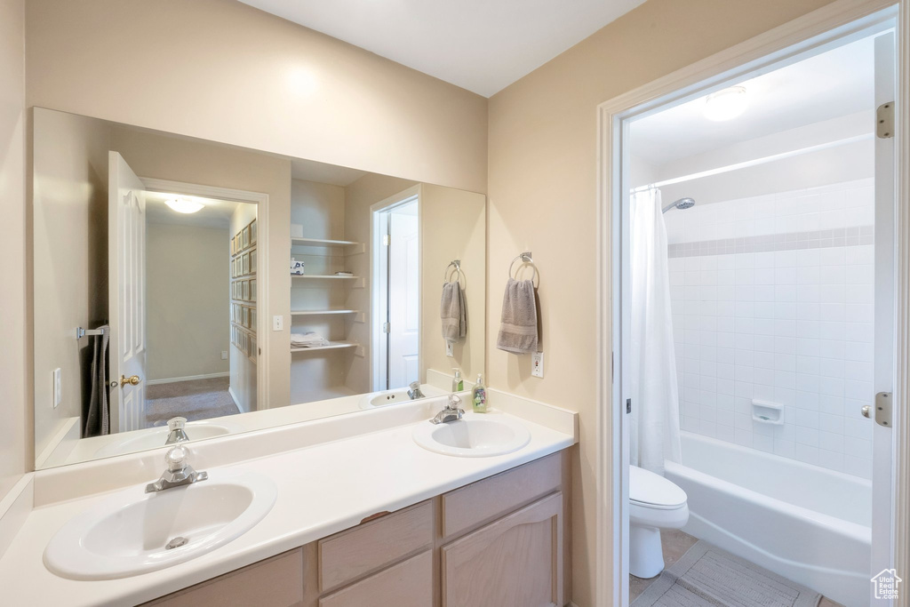 Bathroom featuring double vanity, shower / tub combo, and tile patterned flooring