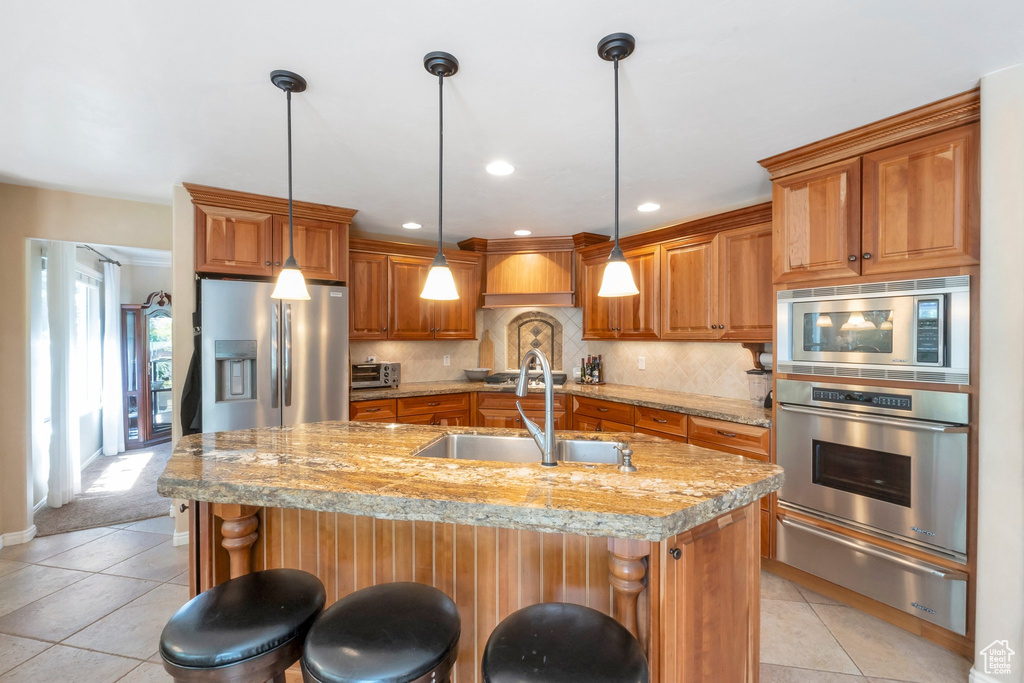 Kitchen with stainless steel appliances, a warming drawer, brown cabinets, light tile patterned floors, and recessed lighting