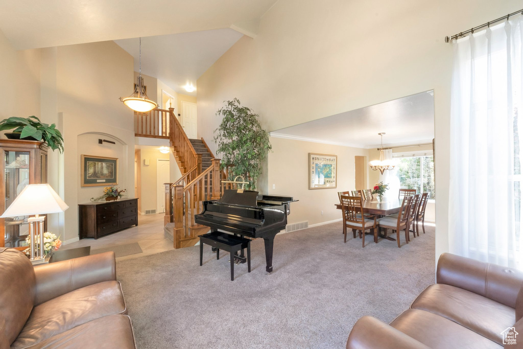 Carpeted living area with a high ceiling, stairs, and a chandelier