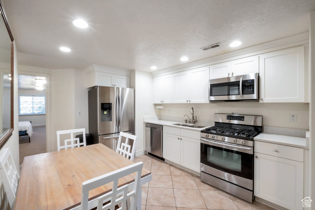 Kitchen with stainless steel appliances, recessed lighting, white cabinets, light countertops, and light tile patterned floors