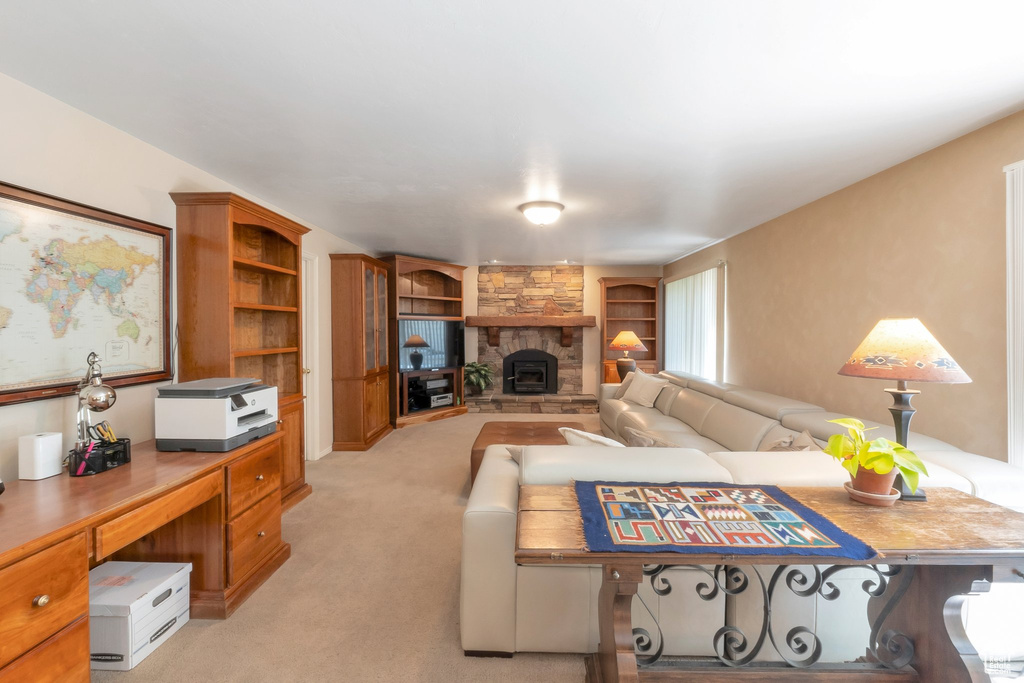 Living room featuring built in shelves, a fireplace, light carpet, and a desk