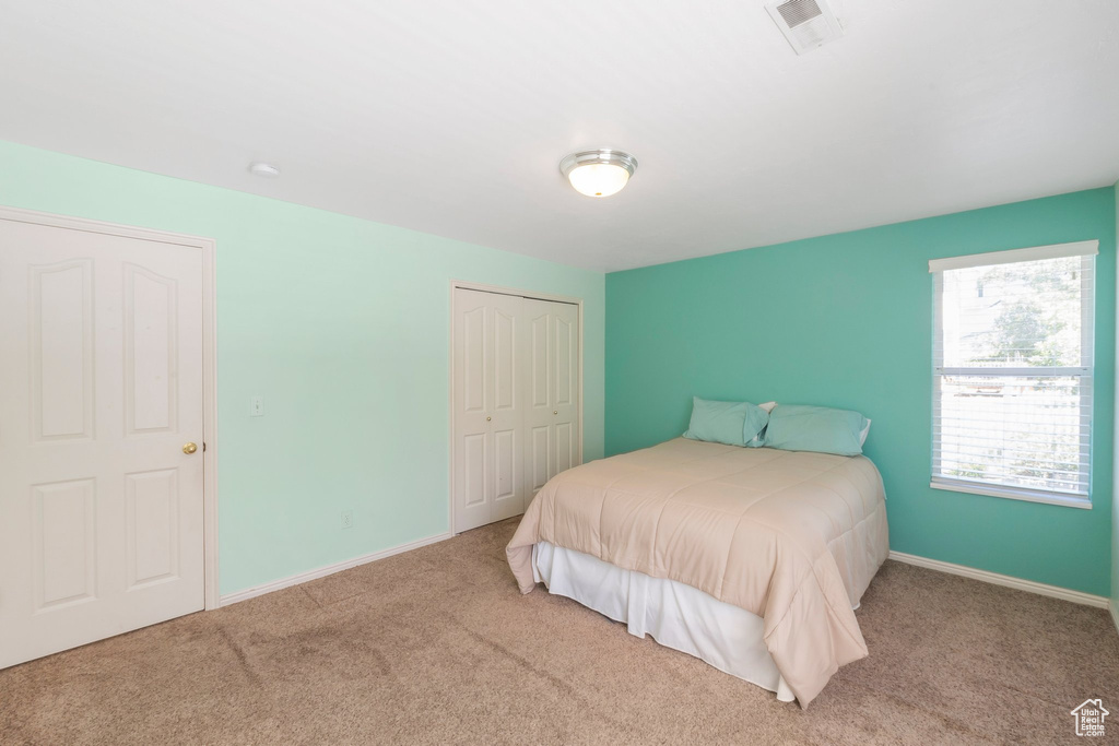 Carpeted bedroom featuring a closet and baseboards