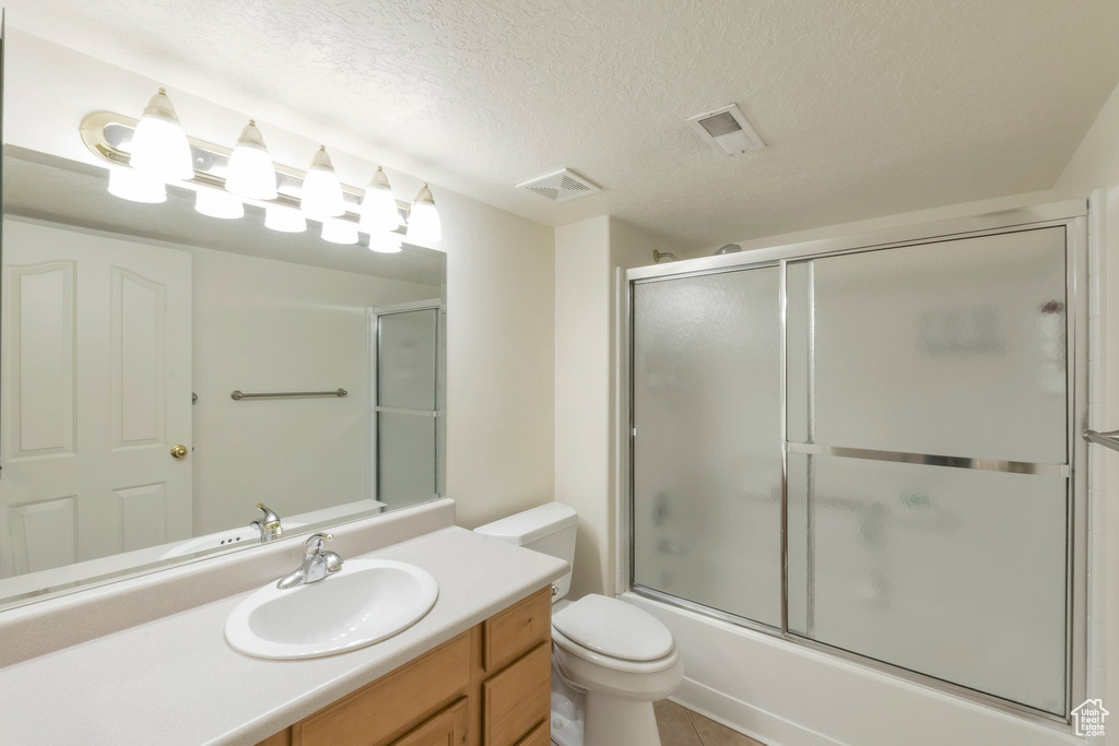 Full bathroom featuring vanity, enclosed tub / shower combo, and a textured ceiling