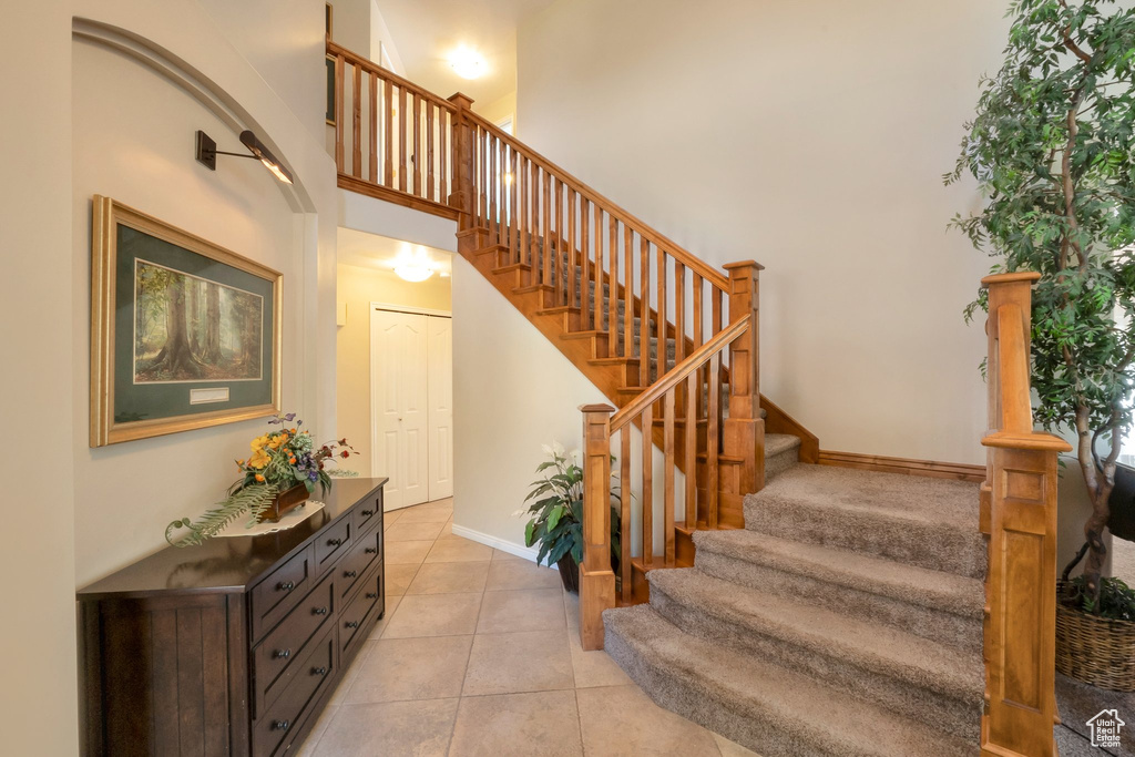 Staircase with a towering ceiling and tile patterned flooring