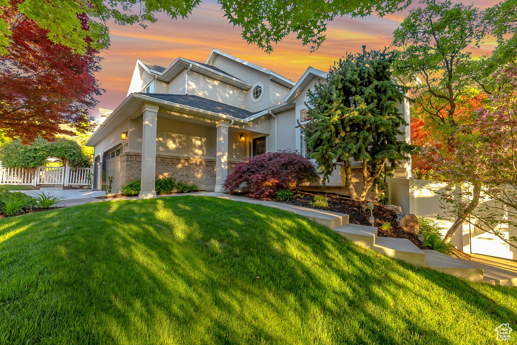 View of front of property featuring stucco siding, an attached garage, brick siding, and driveway