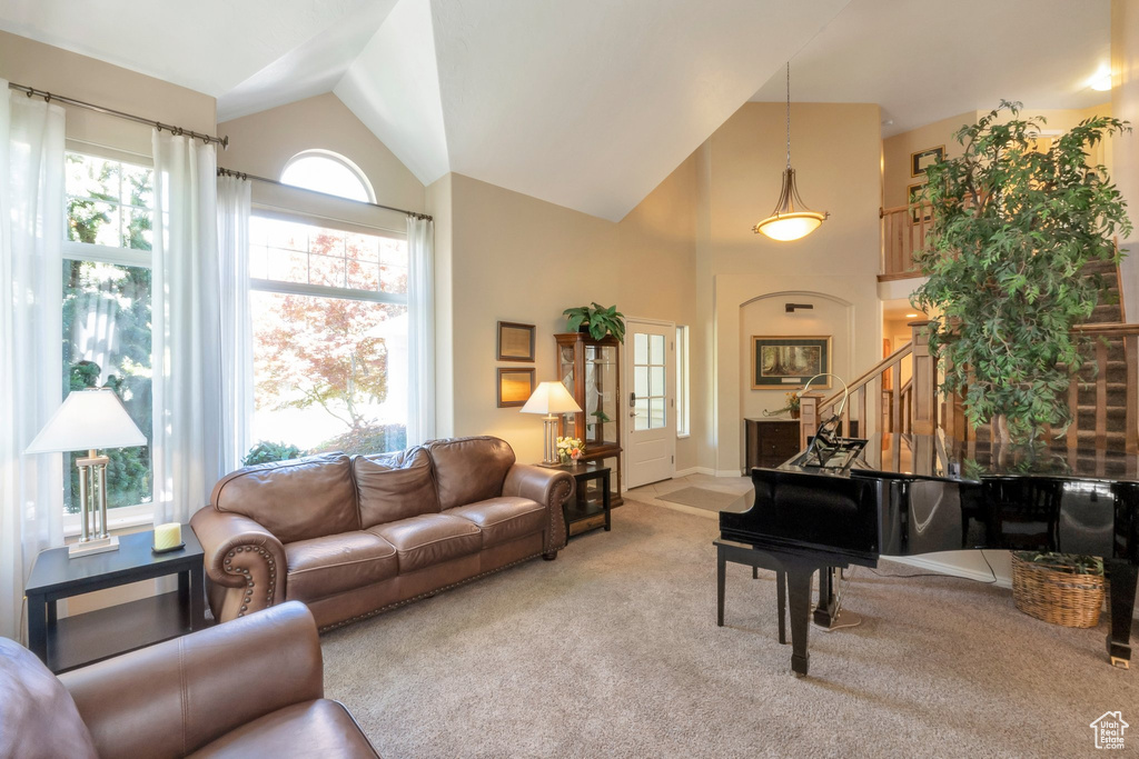 Living room featuring carpet floors, stairs, and high vaulted ceiling