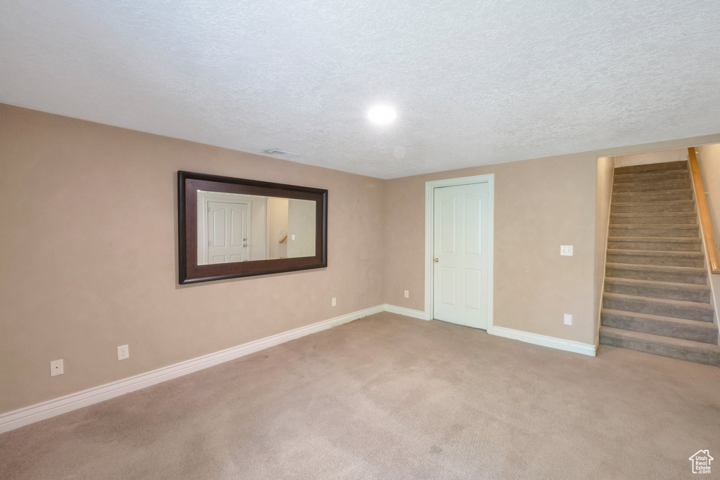 Basement with stairway, carpet, and a textured ceiling