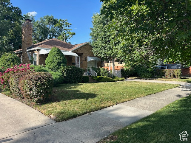 View of front of home featuring a front lawn, brick siding, and a chimney