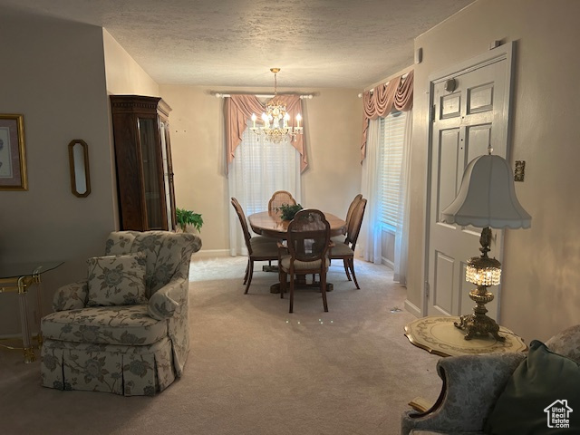 Dining area with a chandelier, light carpet, and a textured ceiling
