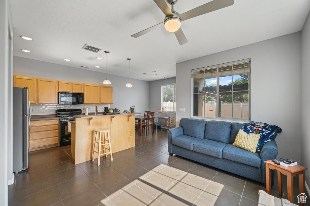 Living room featuring a ceiling fan, recessed lighting, and dark tile patterned flooring