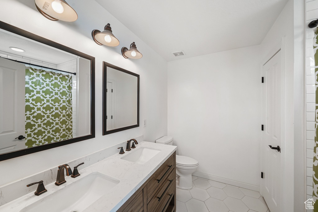 Full bathroom with double vanity, tile patterned floors, and a shower with shower curtain