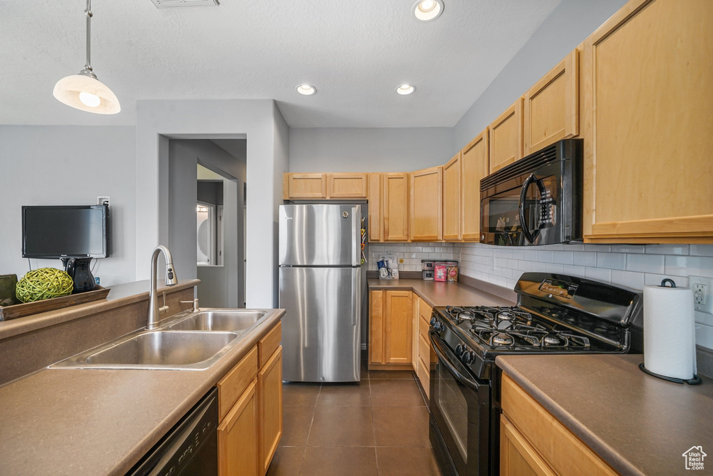 Kitchen featuring black appliances, tasteful backsplash, light brown cabinetry, dark tile patterned floors, and pendant lighting