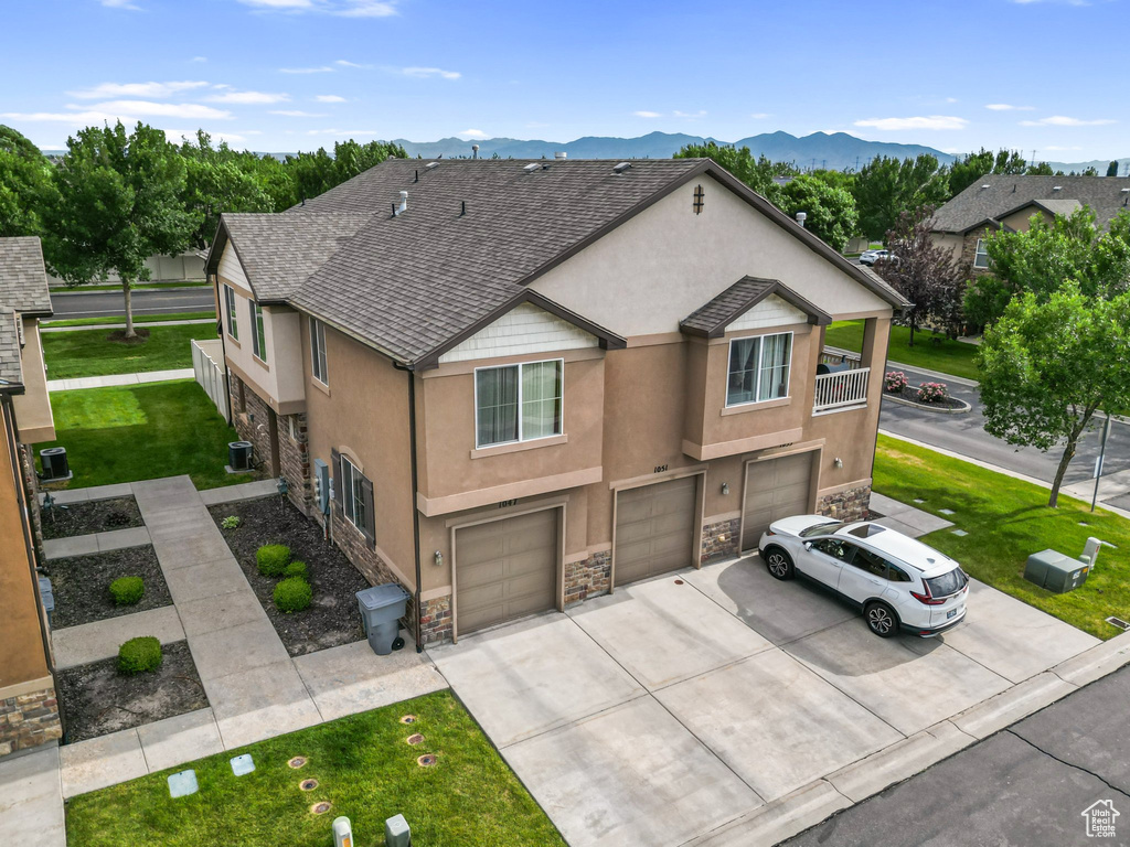 Townhome / multi-family property with stone siding, stucco siding, a garage, and driveway