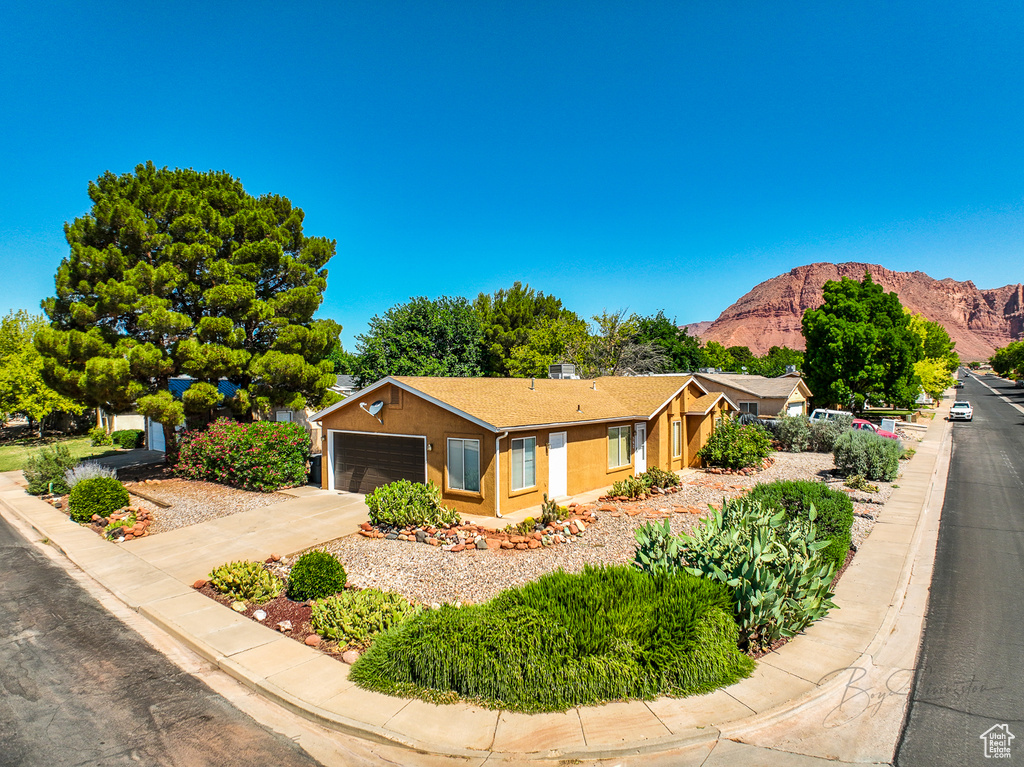 Ranch-style house featuring a mountain view, driveway, stucco siding, and a garage
