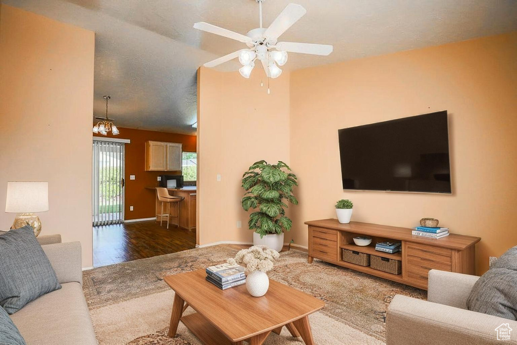 Carpeted living area featuring a ceiling fan, a chandelier, and wood finished floors