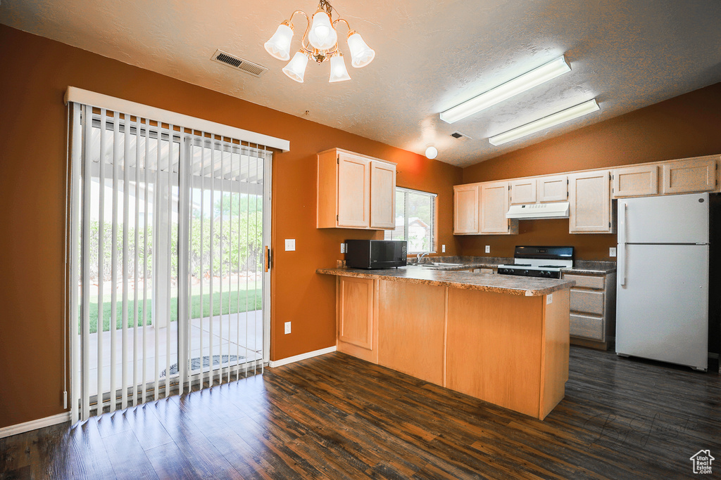 Kitchen with white appliances, under cabinet range hood, lofted ceiling, a peninsula, and dark wood-type flooring