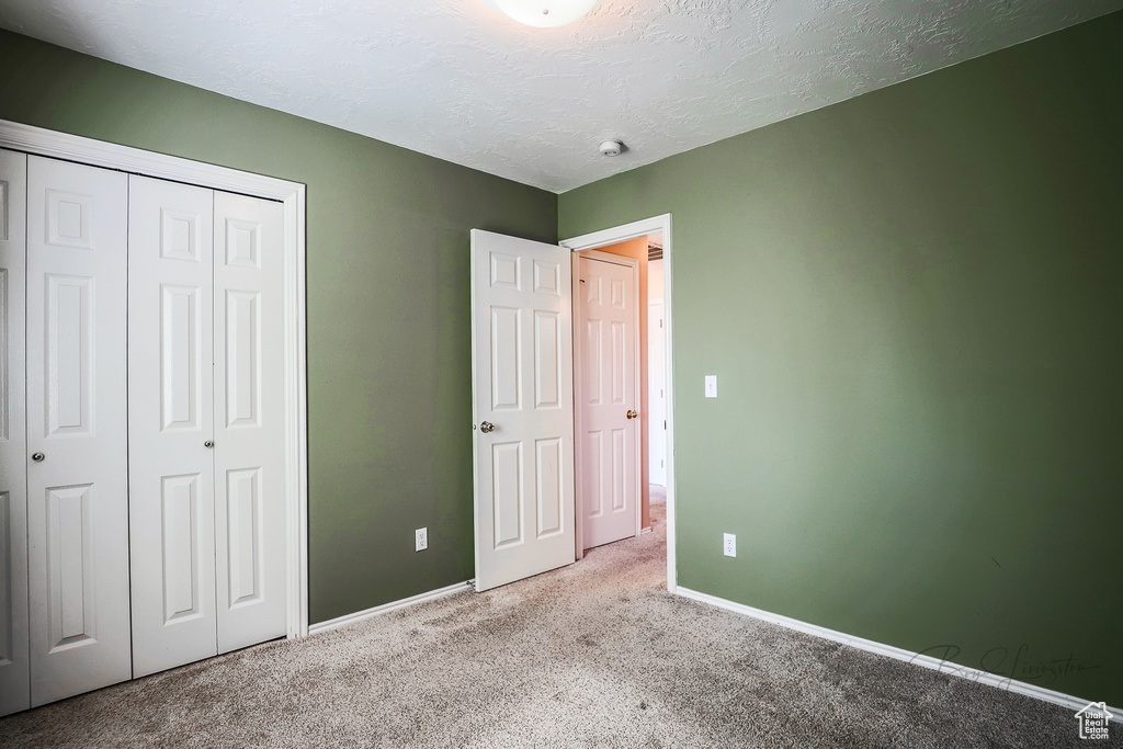 Unfurnished bedroom featuring carpet floors, a closet, and a textured ceiling