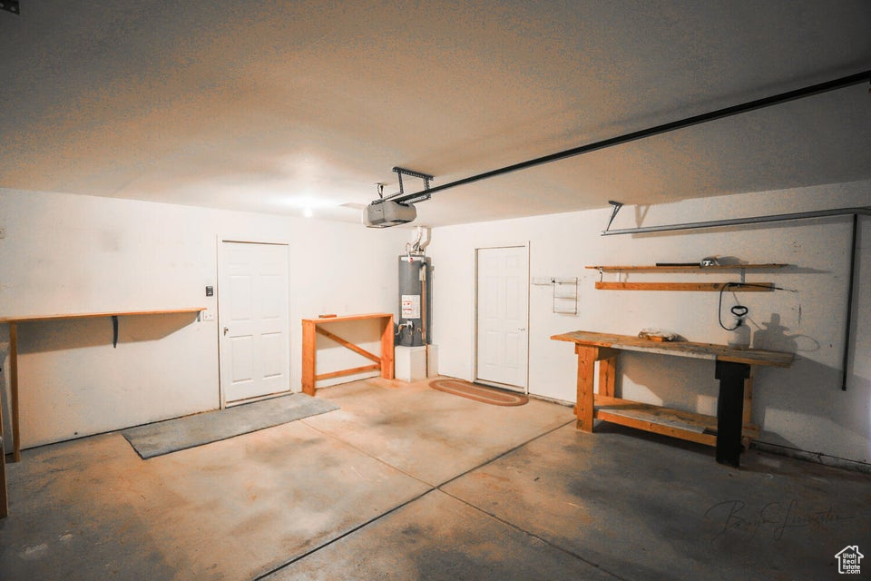 Garage featuring water heater, a workshop area, and a garage door opener