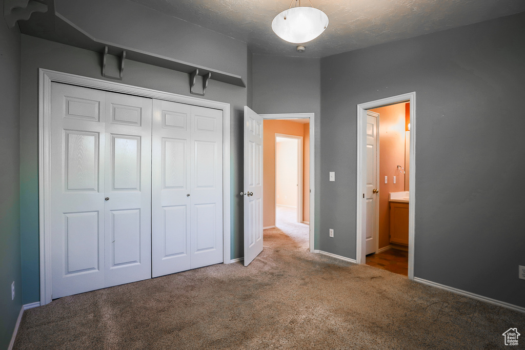 Unfurnished bedroom with carpet floors, a closet, a textured ceiling, and ensuite bathroom