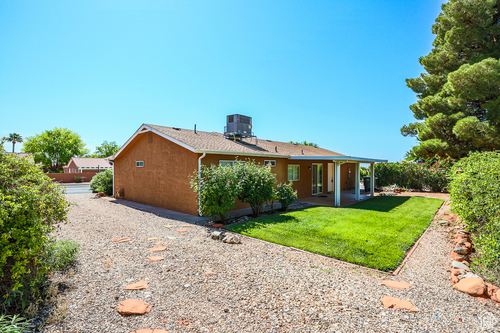 Rear view of property featuring a lawn, a patio, and stucco siding
