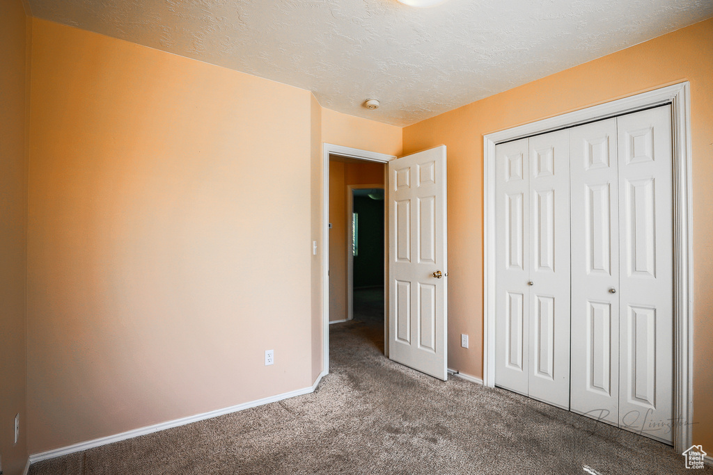 Unfurnished bedroom featuring carpet flooring, a closet, and a textured ceiling