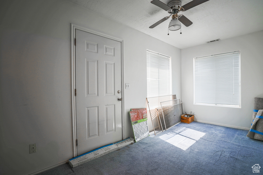 Entrance foyer featuring carpet flooring and a ceiling fan