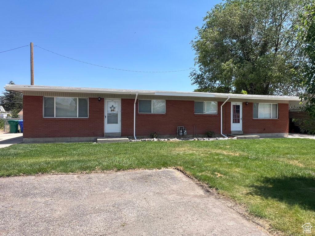 Single story home with entry steps, brick siding, and a front lawn