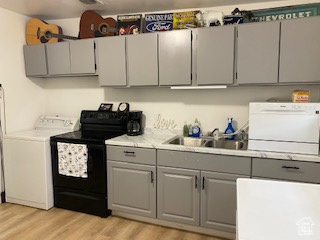 Kitchen featuring gray cabinets, washer / clothes dryer, black / electric stove, and light wood-type flooring
