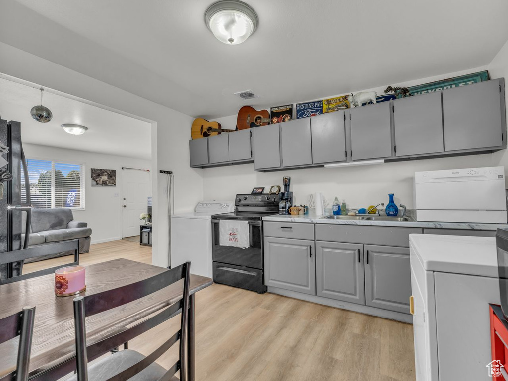 Kitchen with black range with electric cooktop, gray cabinets, light wood-style flooring, washer / clothes dryer, and light countertops