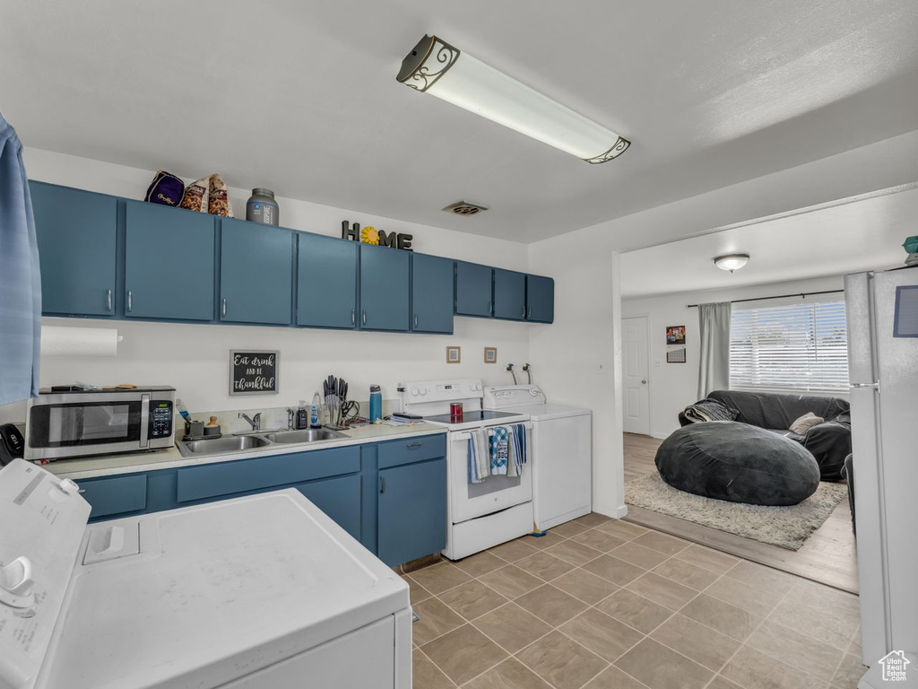 Kitchen with blue cabinetry, white appliances, and light countertops