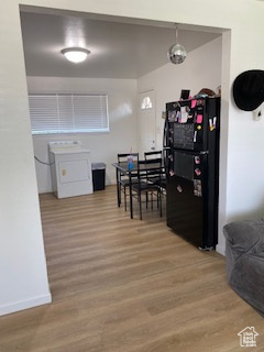 Kitchen with freestanding refrigerator, washer / dryer, and wood finished floors
