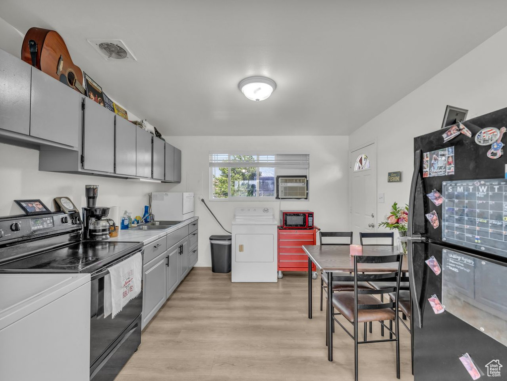 Kitchen with washer / dryer, freestanding refrigerator, electric range, light wood finished floors, and gray cabinetry