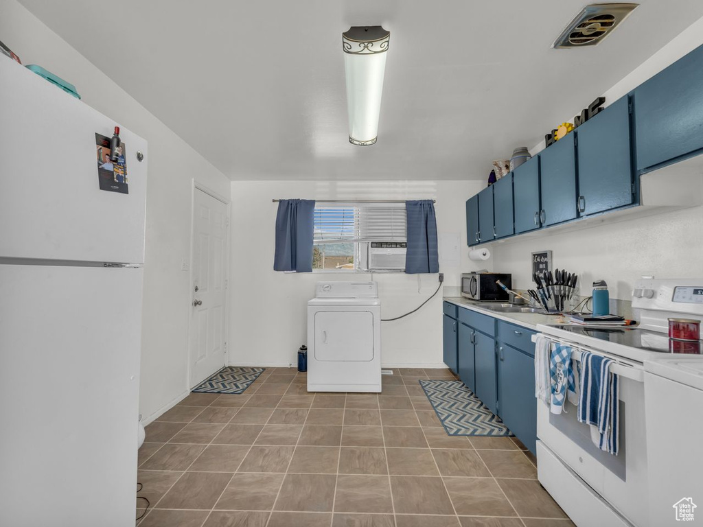 Kitchen with white appliances, washer / dryer, blue cabinets, light countertops, and tile patterned floors