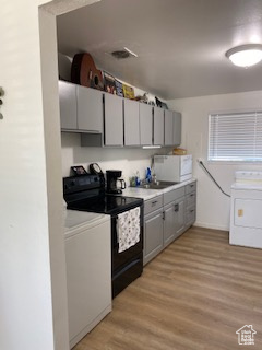 Kitchen featuring electric range, washer / dryer, gray cabinetry, and white microwave