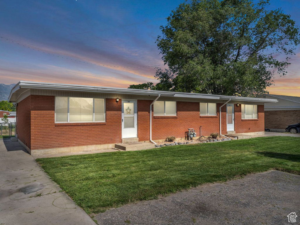Ranch-style home with entry steps, brick siding, and a yard