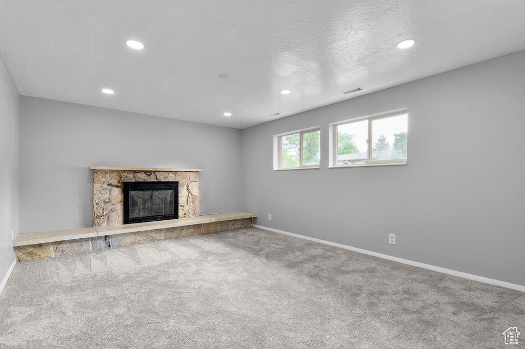 Unfurnished living room featuring recessed lighting, carpet, and a stone fireplace