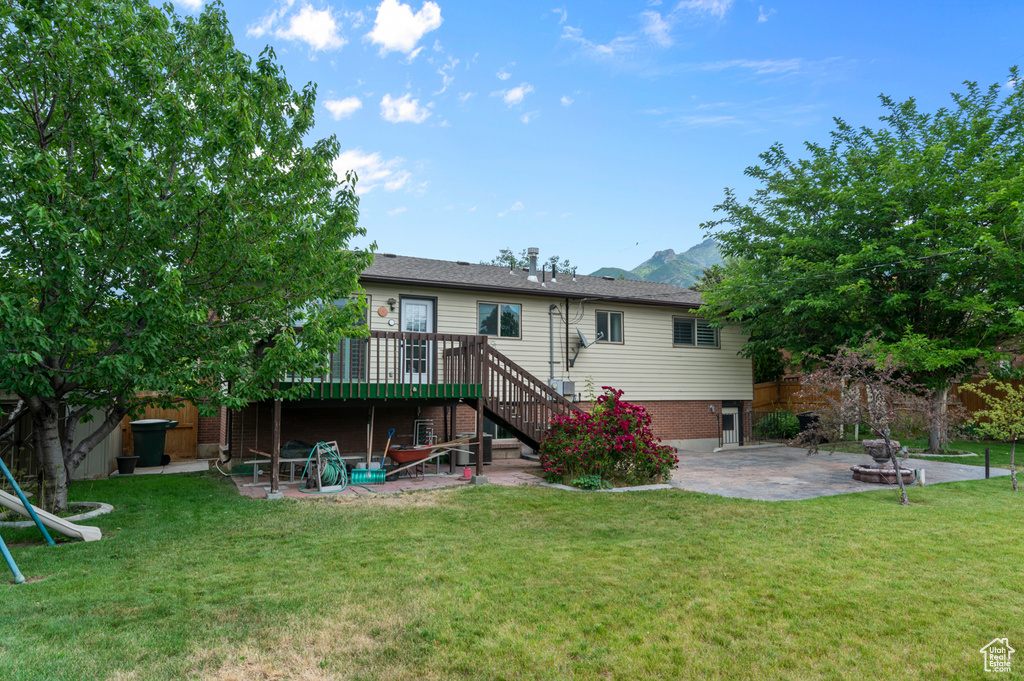 Back of house featuring a patio, stairs, a deck with mountain view, and a lawn